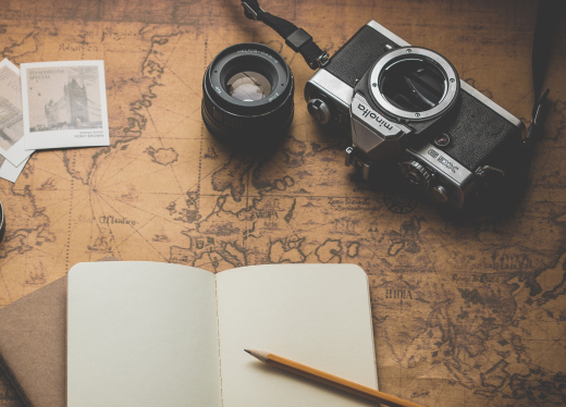 A notebook, camera, and map arranged together, suggesting travel planning and exploration.