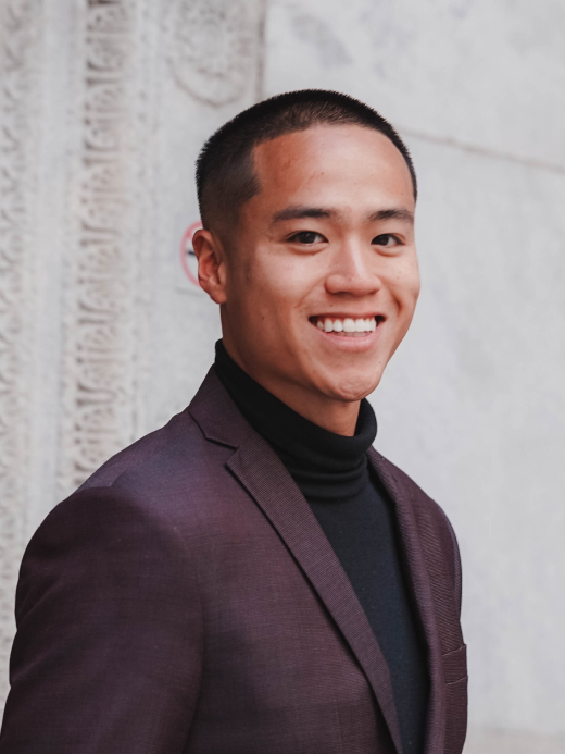A young man wearing a suit over a turtleneck sweater, exuding a professional and stylish appearance.